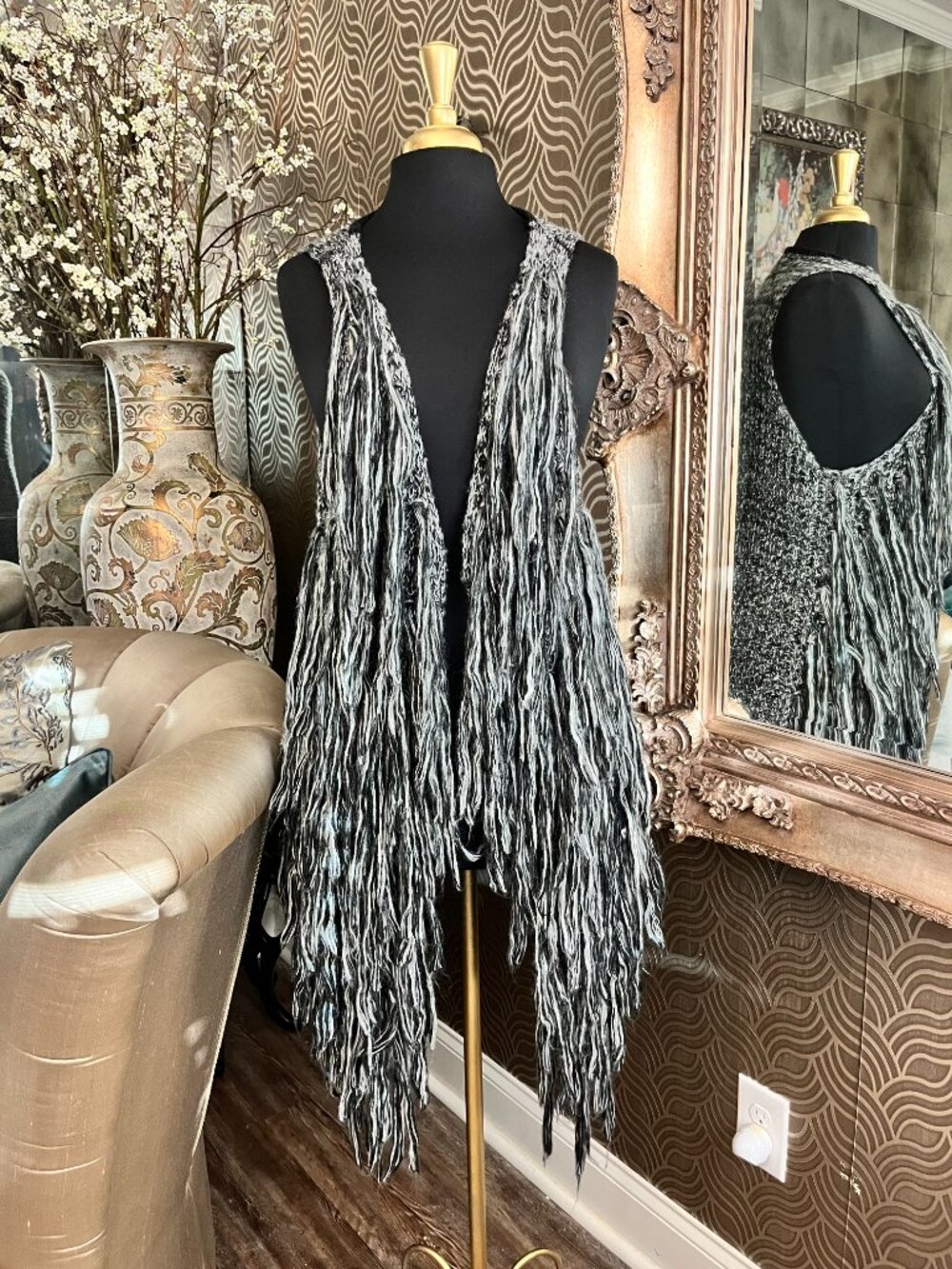 gray sweater vest features a dramatic fringe design
